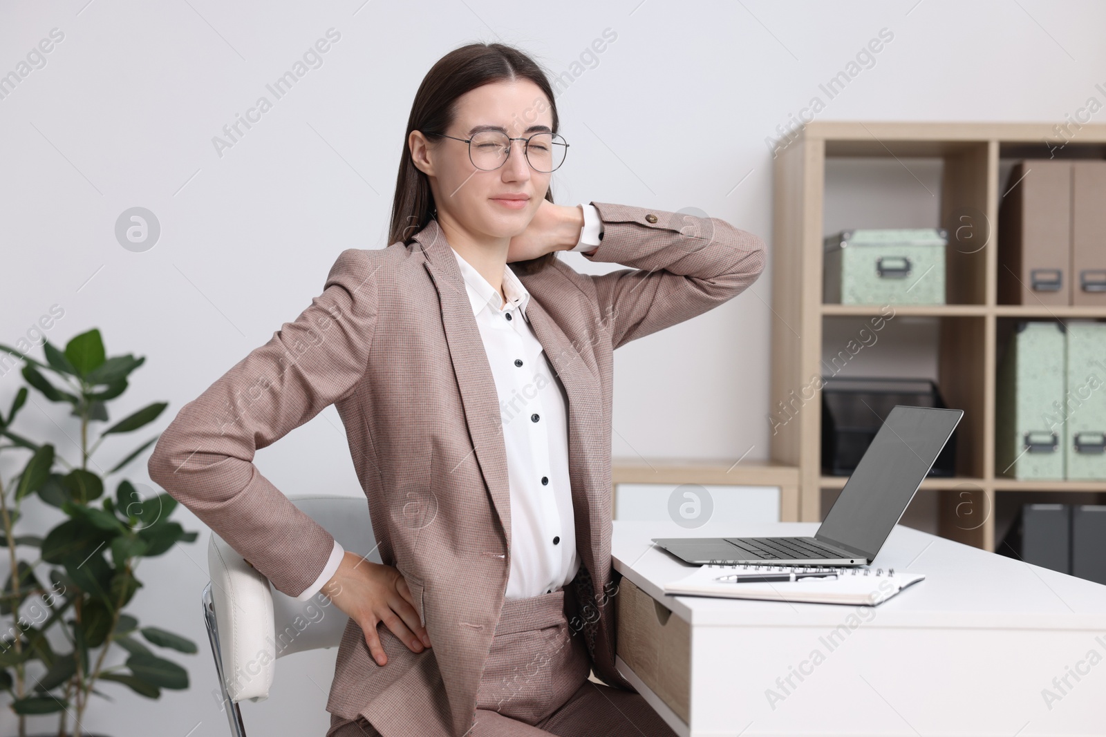 Photo of Woman suffering from neck pain in office. Symptom of poor posture