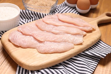 Cooking schnitzel. Raw meat, flour, eggs and breadcrumbs on wooden table