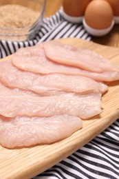 Photo of Cooking schnitzel. Raw meat, eggs and breadcrumbs on table, closeup