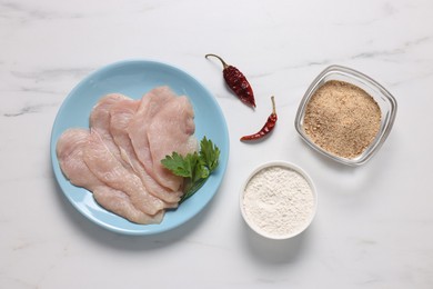 Photo of Cooking schnitzel. Raw meat, flour, chili pepper and breadcrumbs on white marble table, top view