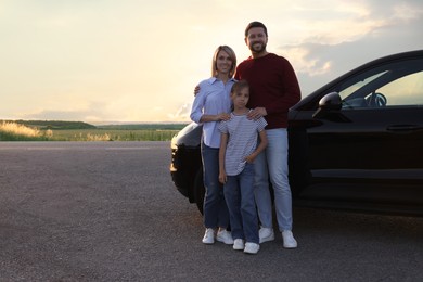 Happy parents and their daughter near car outdoors, space for text