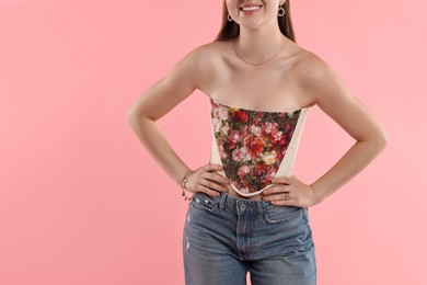 Photo of Smiling woman in stylish corset on pink background, closeup. Space for text