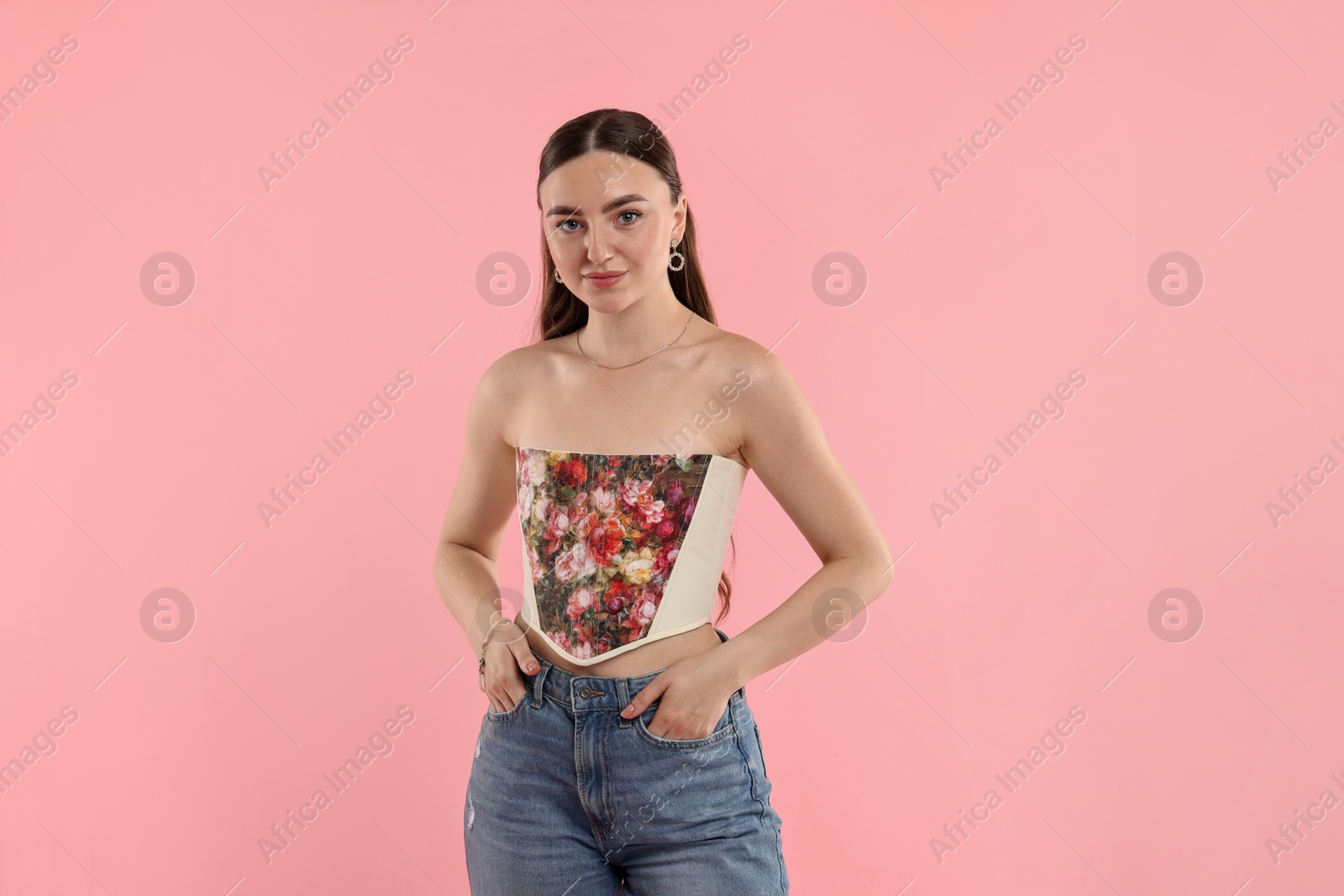 Photo of Beautiful woman in stylish corset posing on pink background