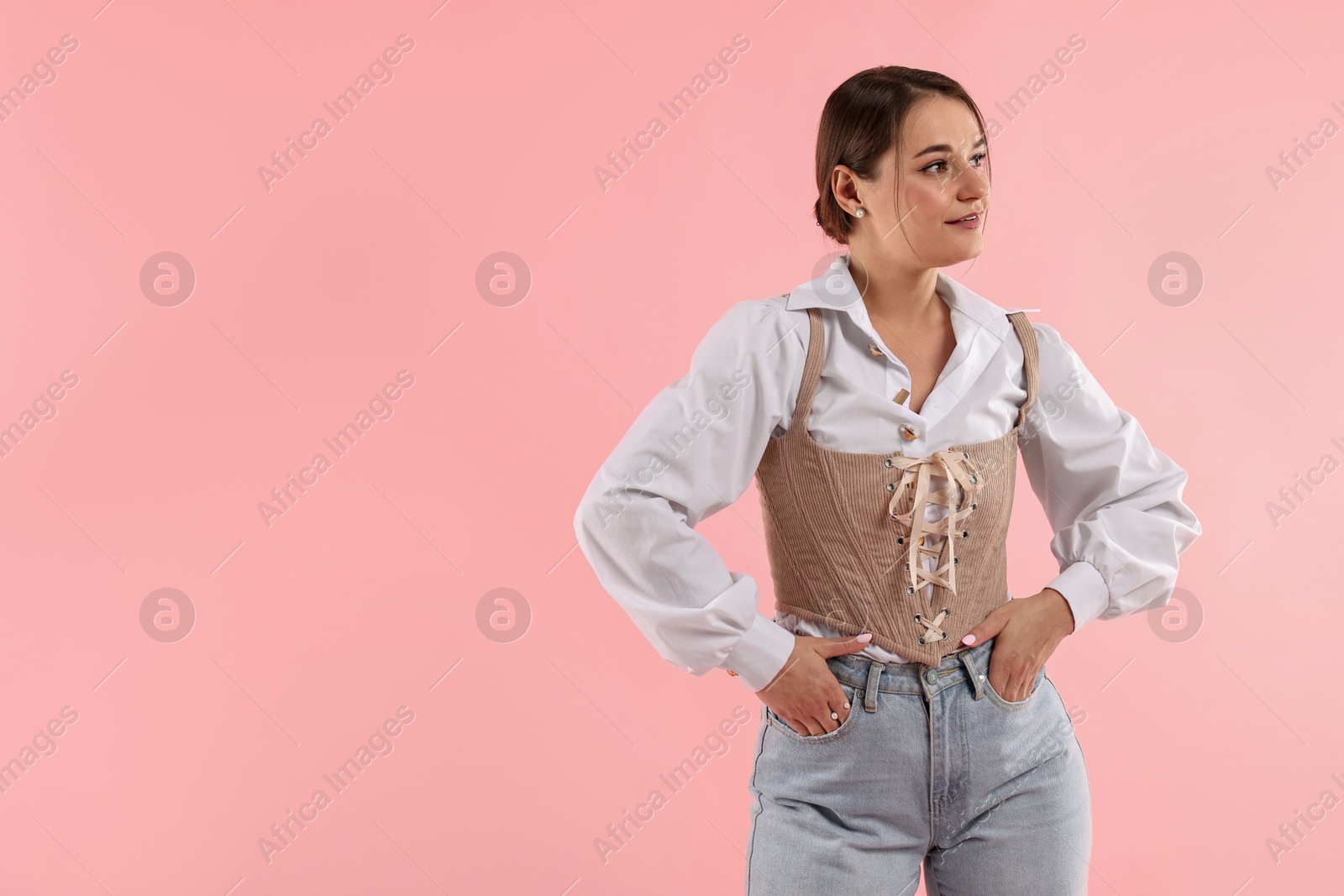 Photo of Smiling woman in stylish corset on pink background. Space for text