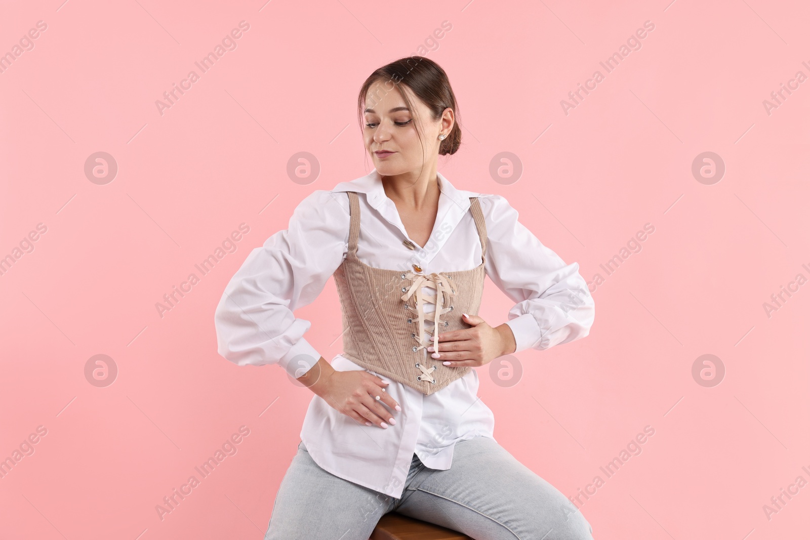 Photo of Beautiful woman in stylish corset posing on pink background
