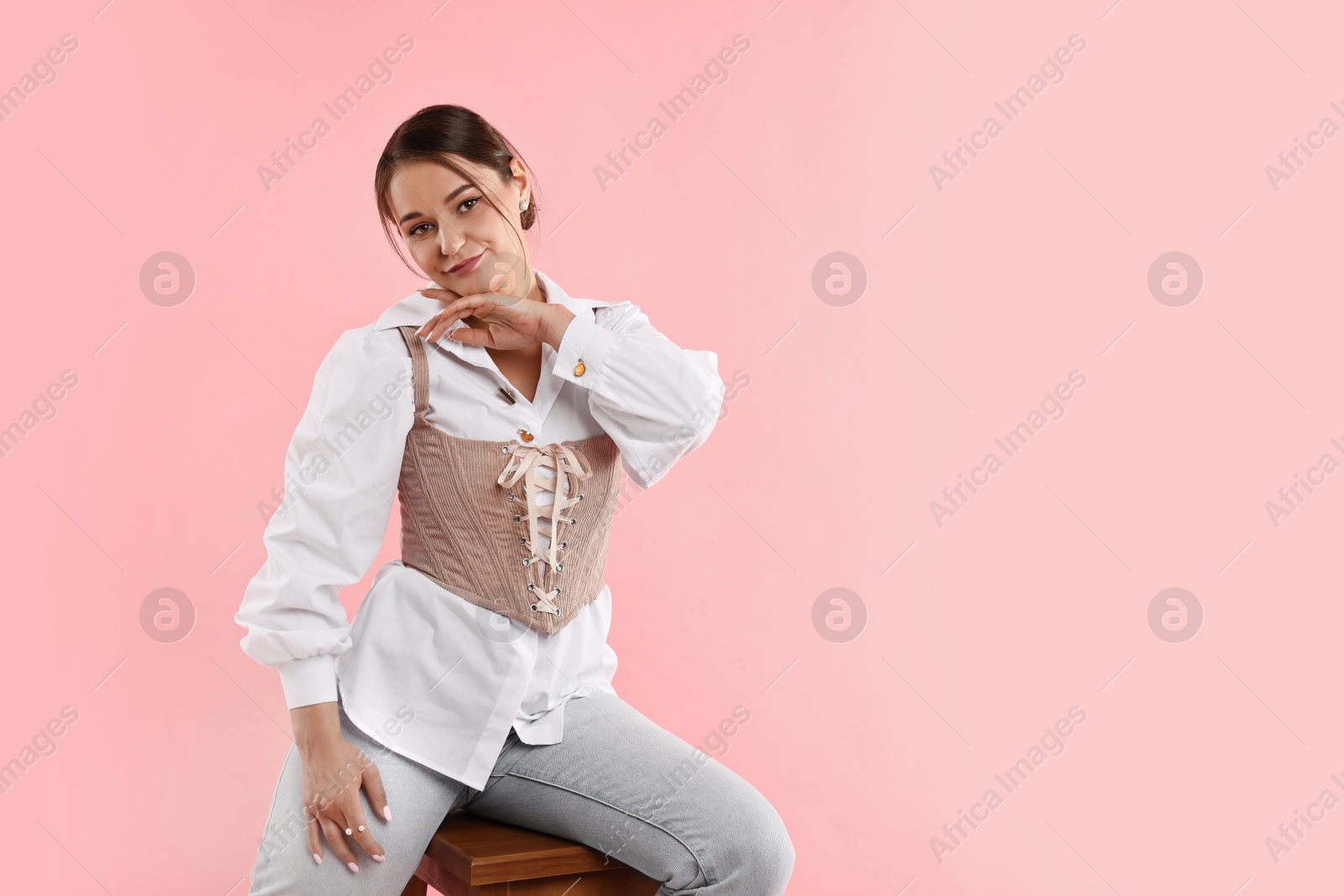 Photo of Beautiful woman in stylish corset posing on pink background. Space for text