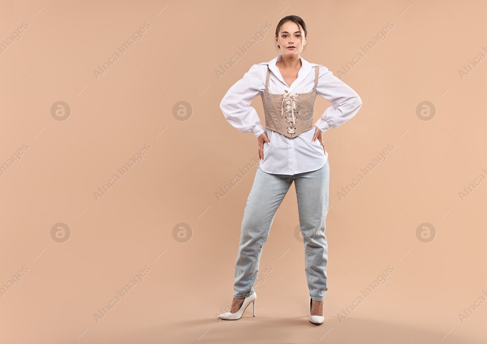 Photo of Beautiful woman in stylish corset posing on beige background. Space for text