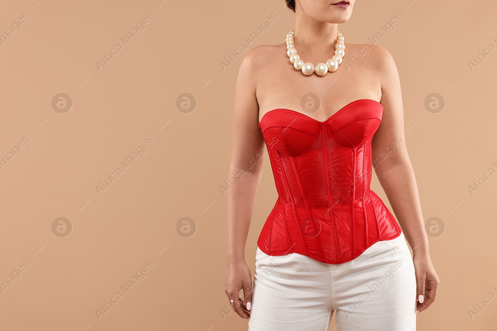 Photo of Woman in red corset on beige background, closeup. Space for text