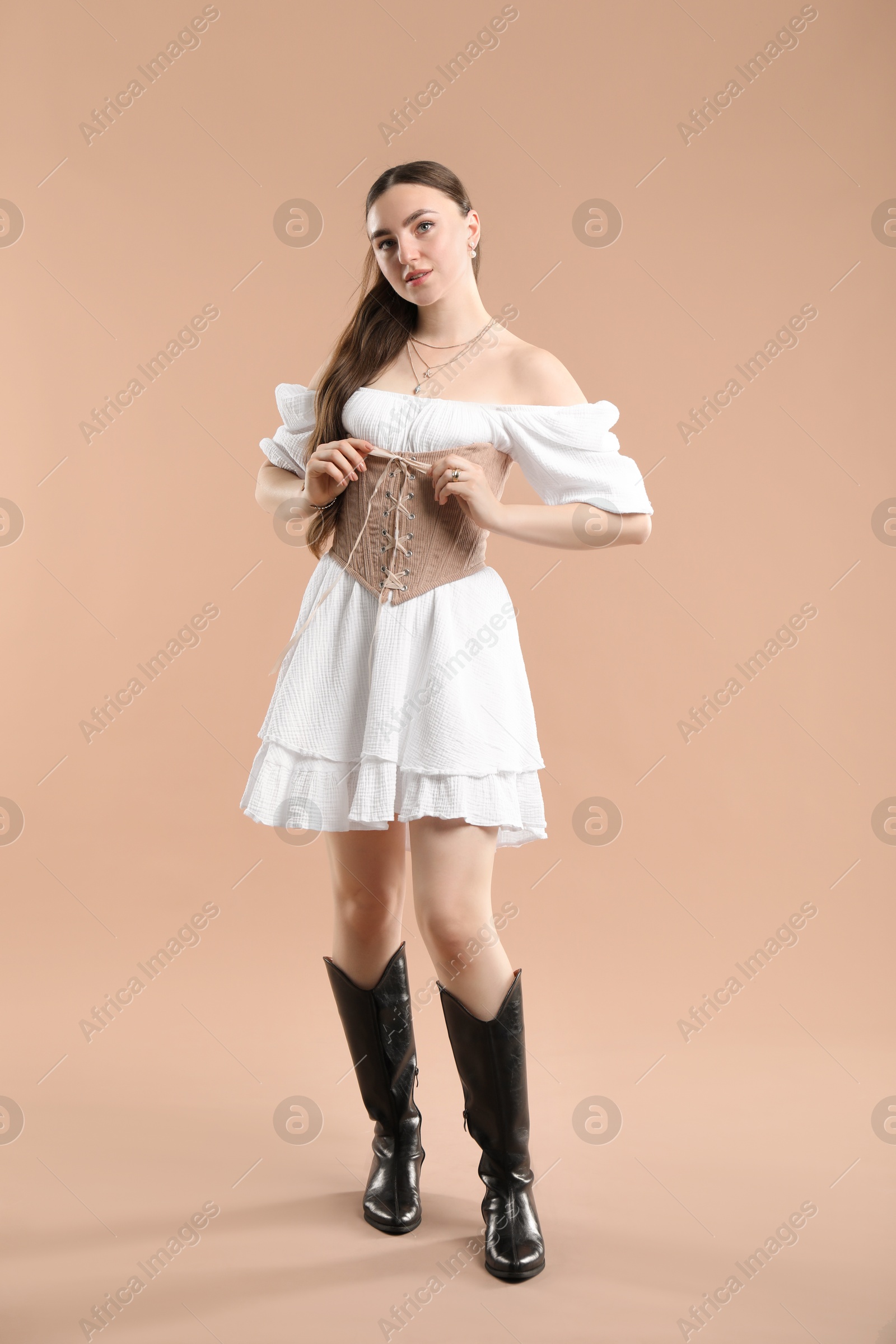 Photo of Beautiful woman in velvet corset on beige background