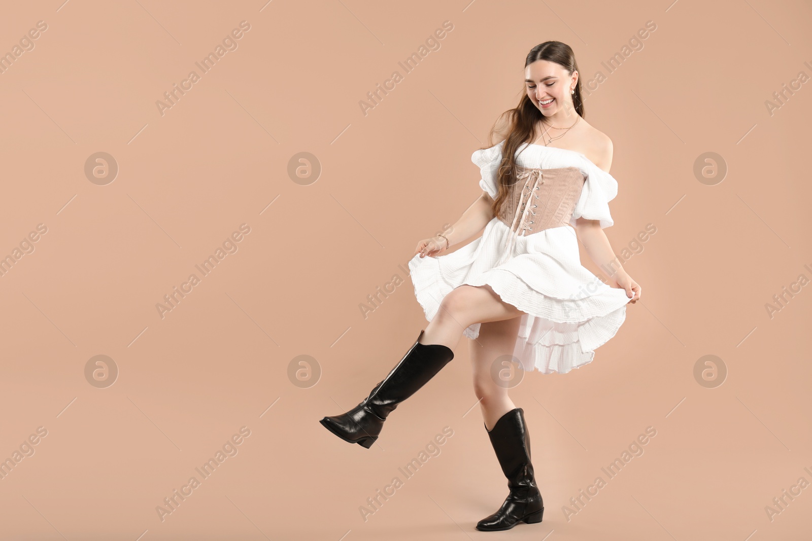 Photo of Smiling woman in velvet corset on beige background. Space for text