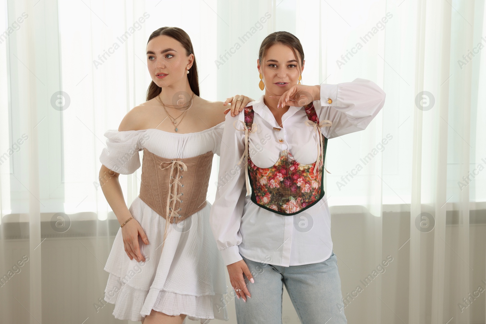 Photo of Beautiful women in stylish corsets posing indoors