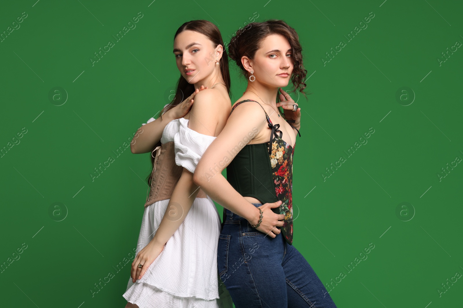 Photo of Beautiful women in stylish corsets on green background