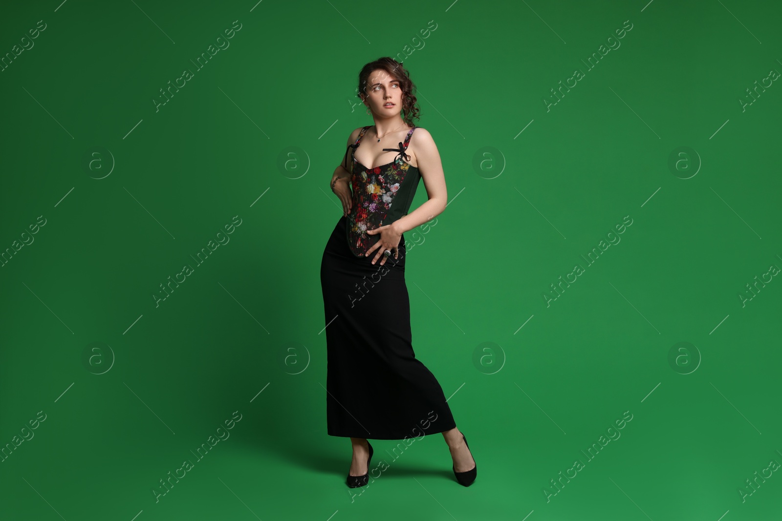 Photo of Beautiful woman in stylish corset posing on green background