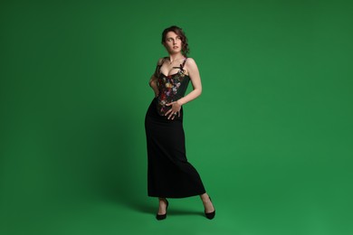 Photo of Beautiful woman in stylish corset posing on green background