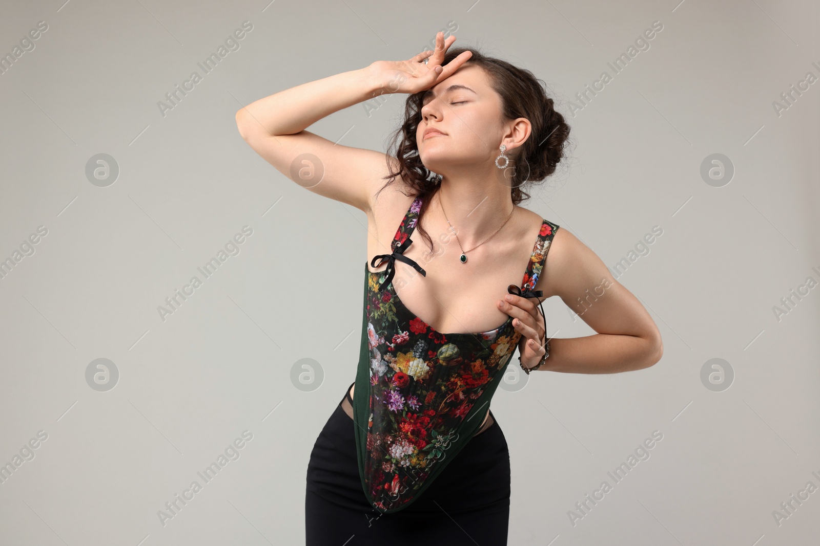 Photo of Beautiful woman in stylish corset posing on light grey background