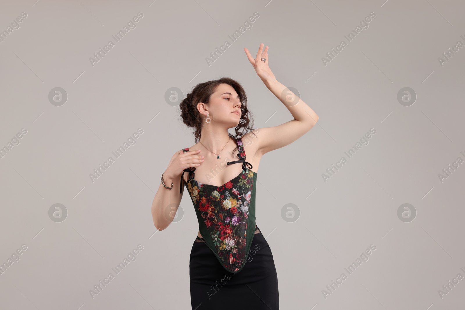 Photo of Beautiful woman in stylish corset posing on light grey background