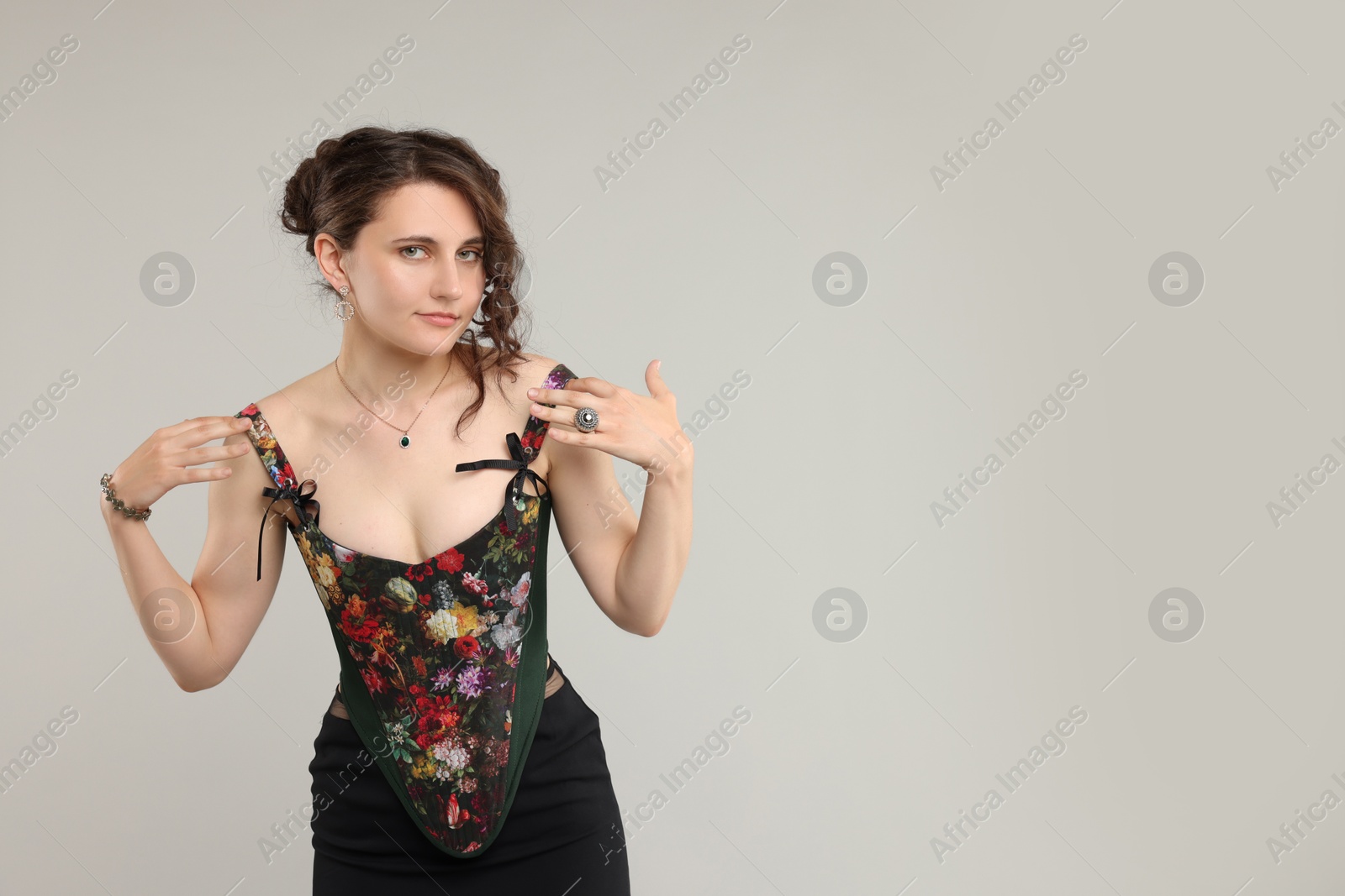 Photo of Beautiful woman in stylish corset posing on light grey background. Space for text