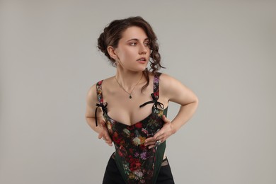 Photo of Beautiful woman in stylish corset posing on grey background