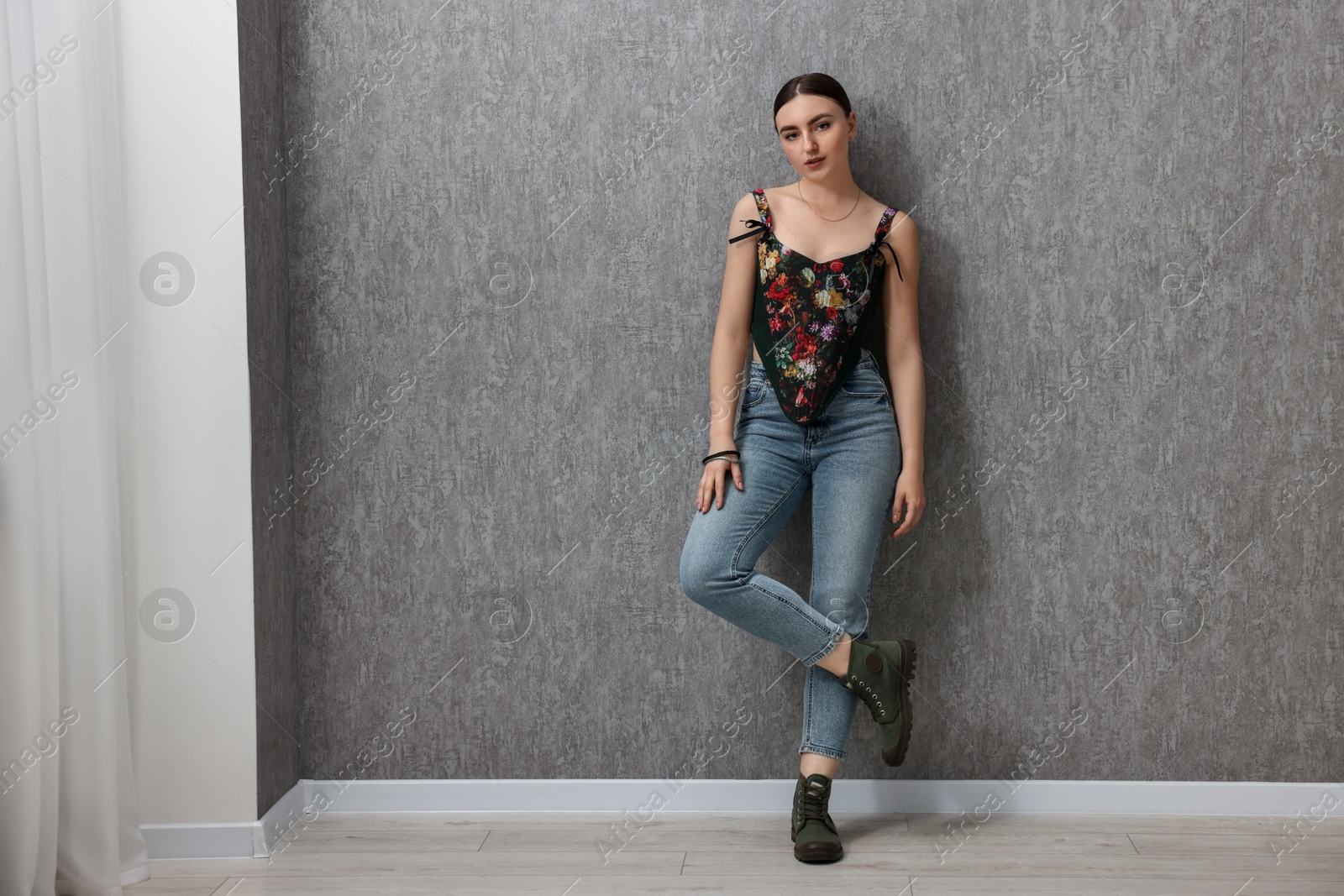 Photo of Beautiful young woman in stylish corset near grey wall