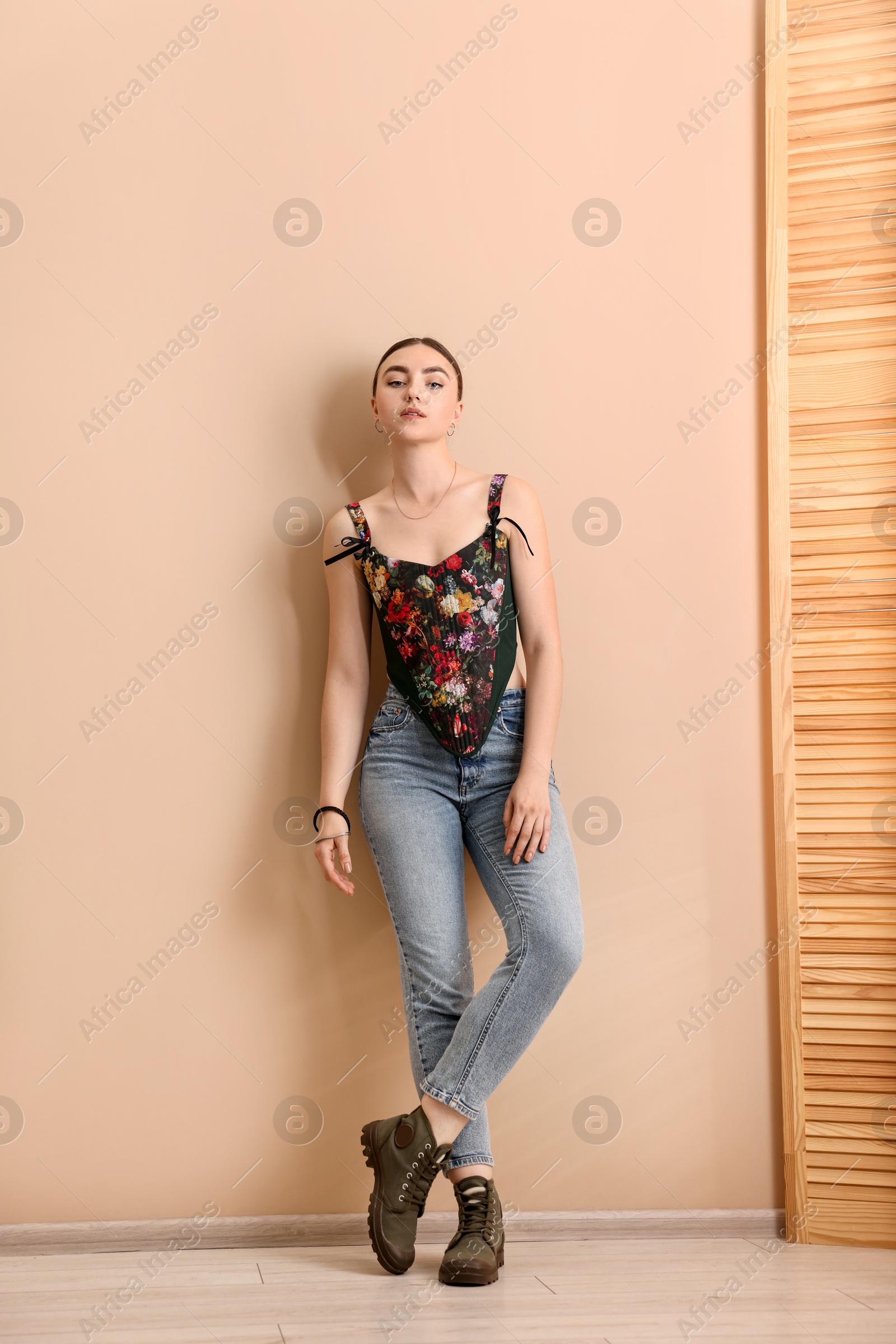 Photo of Beautiful young woman in stylish corset near beige wall