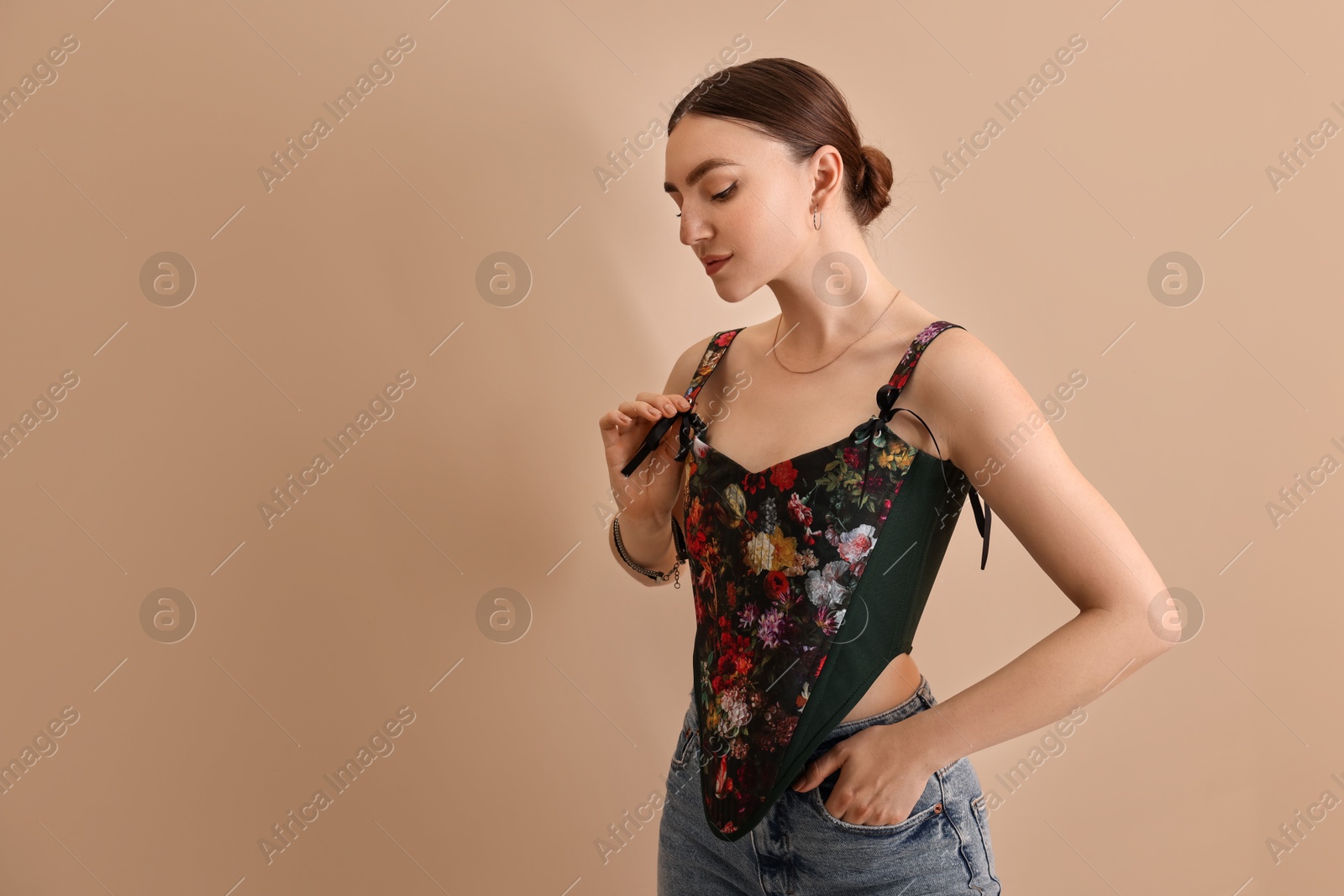 Photo of Beautiful young woman in stylish corset on beige background. Space for text