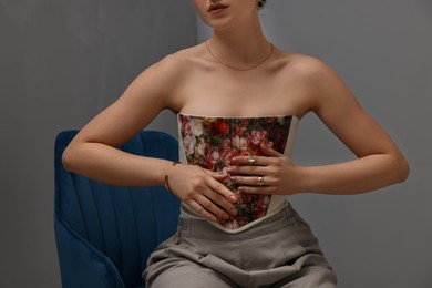 Photo of Woman in stylish corset on armchair indoors, closeup