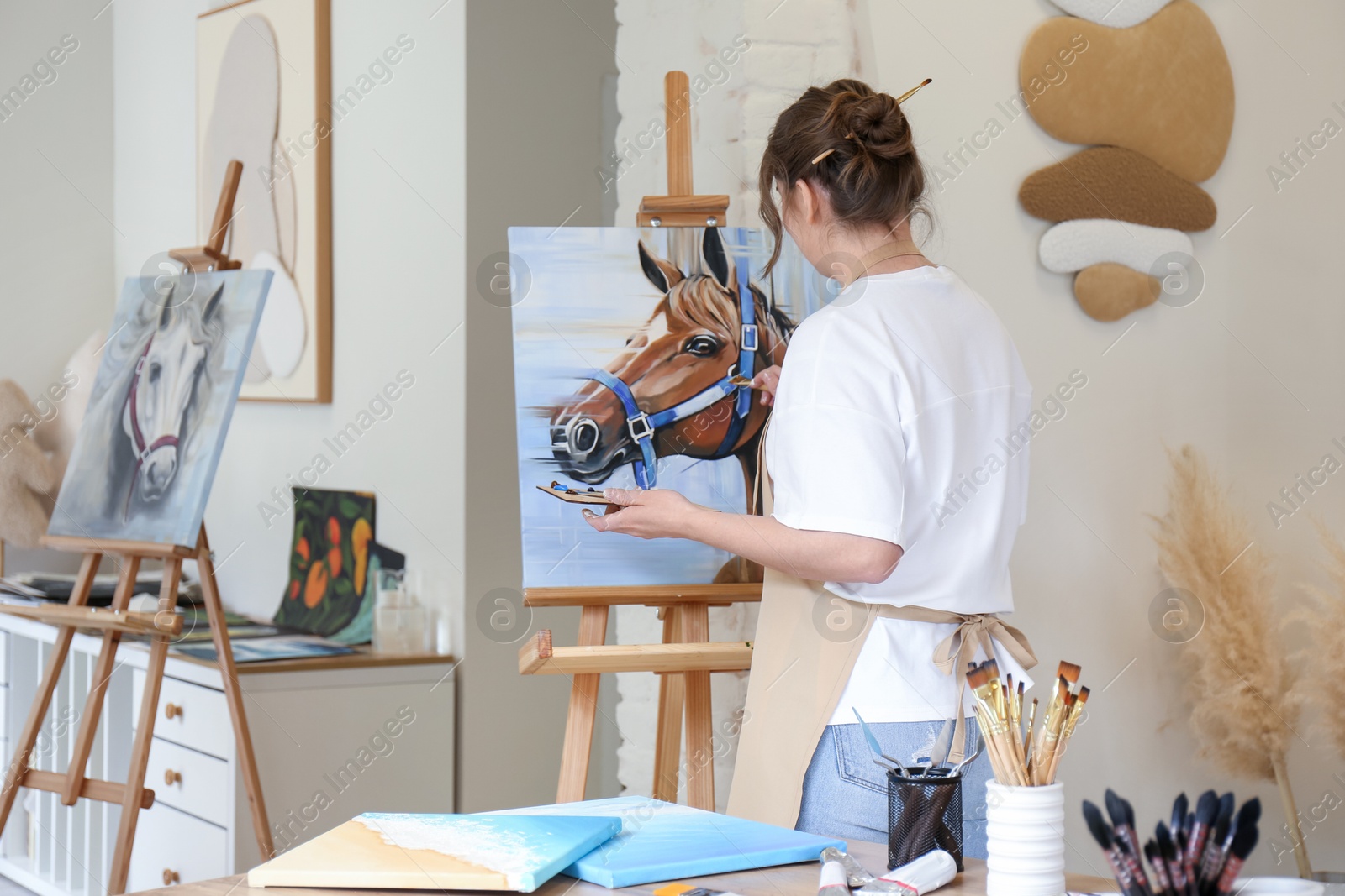 Photo of Woman drawing cute horse with brush in studio