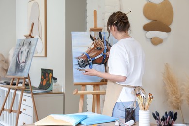 Woman drawing cute horse with brush in studio