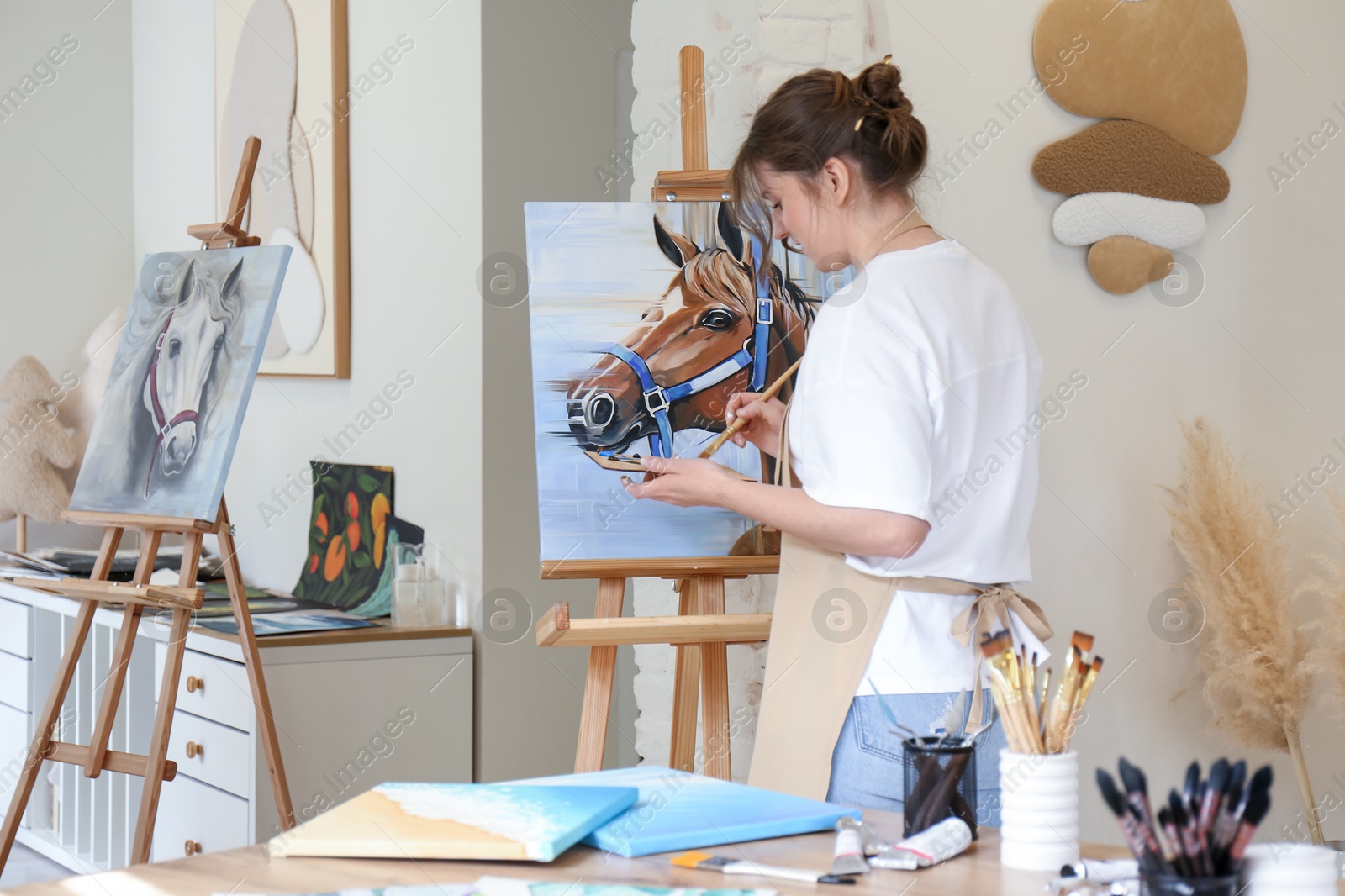 Photo of Woman drawing cute horse with brush in studio