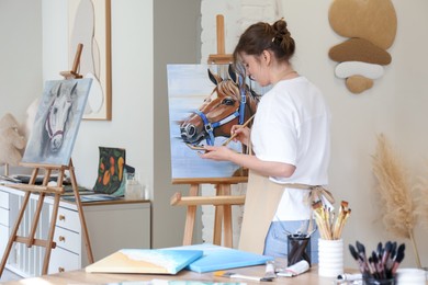 Woman drawing cute horse with brush in studio