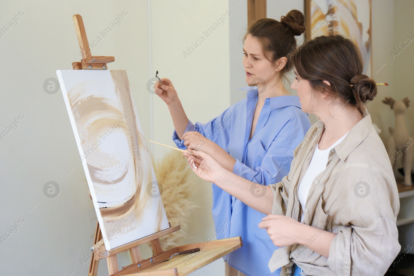 Photo of Artist teaching her student to paint in studio