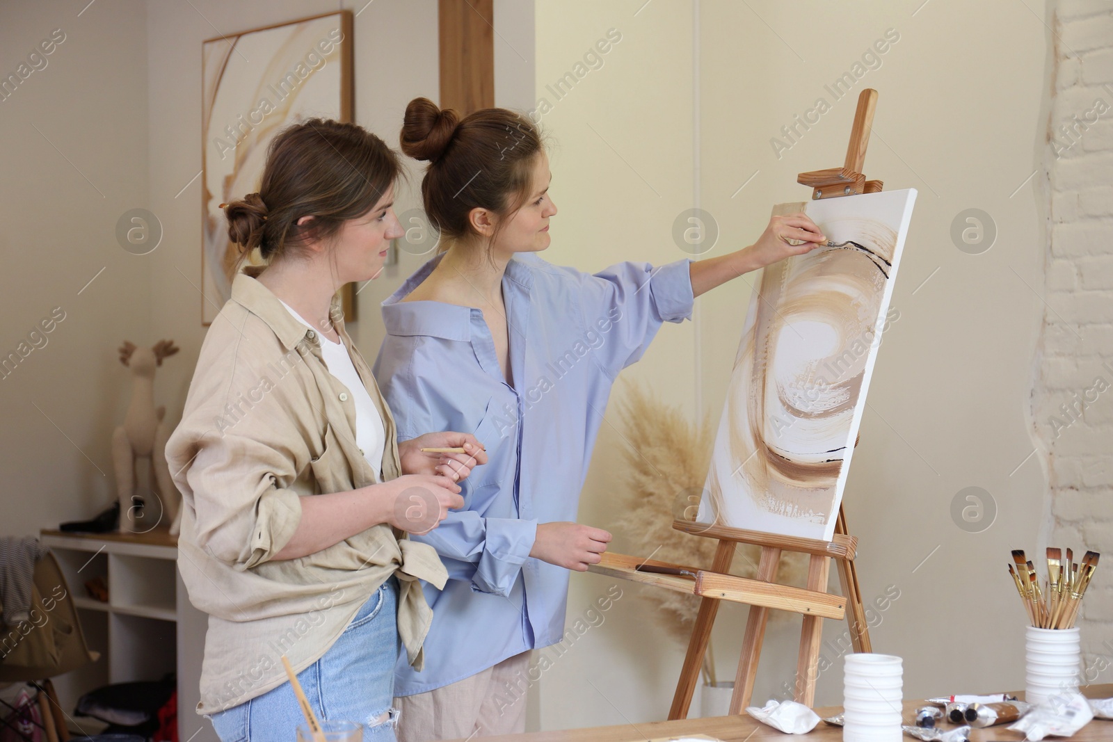 Photo of Artist teaching her student to paint in studio