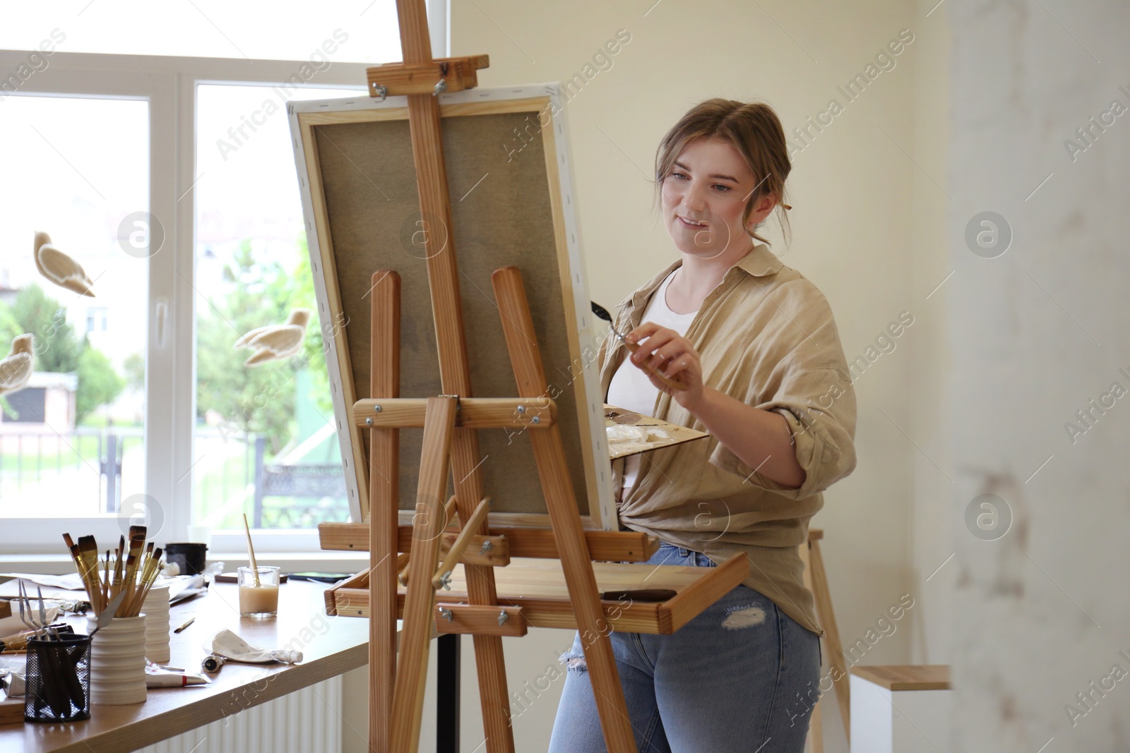 Photo of Woman with palette knife drawing picture in studio