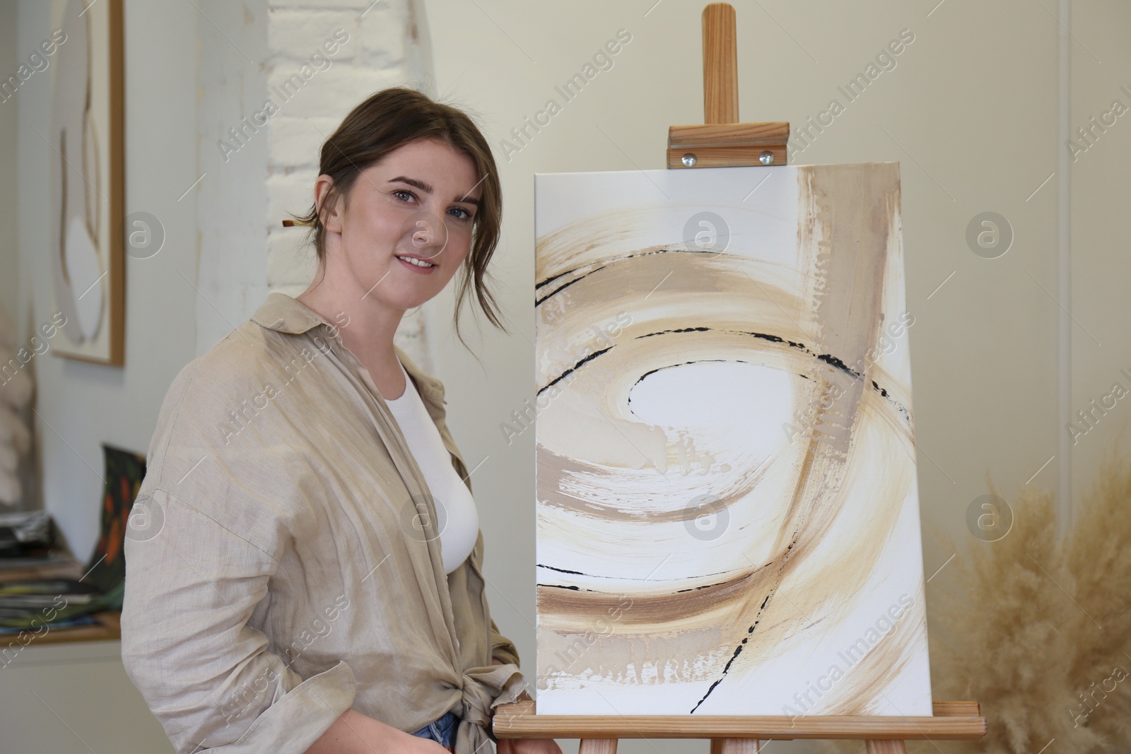 Photo of Portrait of smiling woman with her artwork in drawing studio