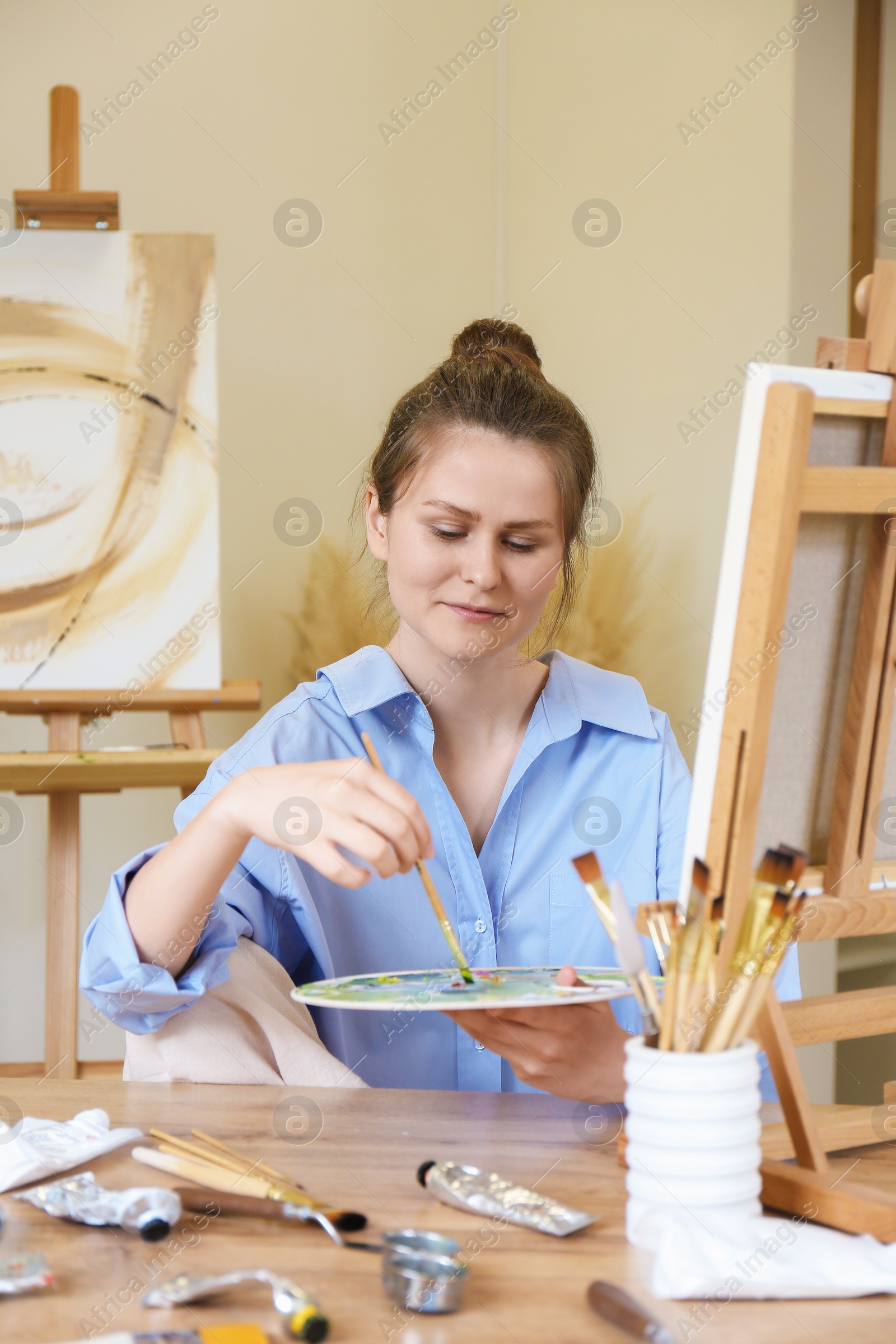 Photo of Woman with brush drawing picture at table in studio