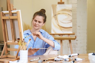 Woman with brush drawing picture at table in studio