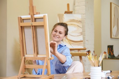 Photo of Smiling woman with brush drawing picture at table in studio
