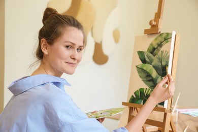 Photo of Woman with brush painting tropical leaves in studio