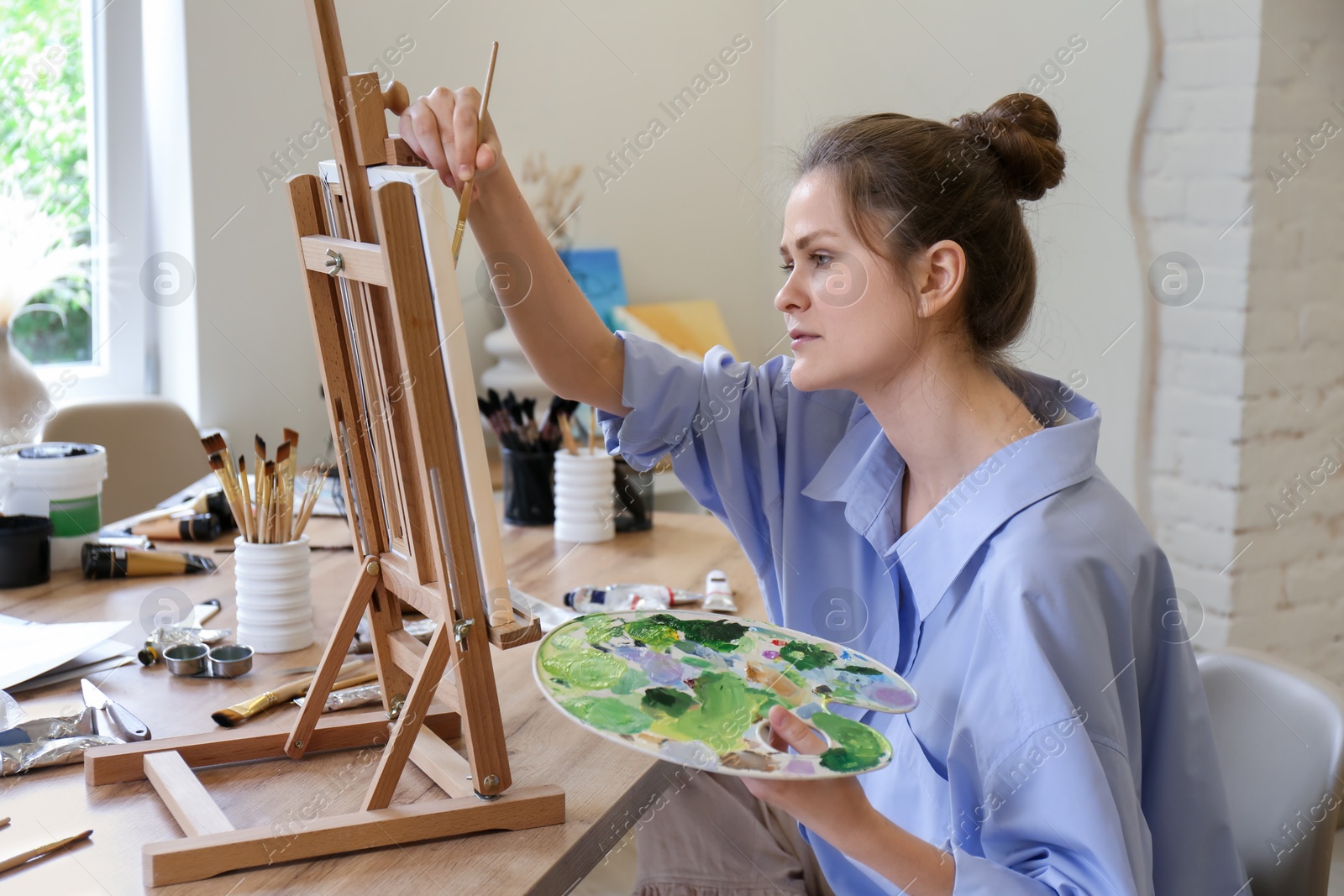 Photo of Woman with brush drawing picture at table in studio