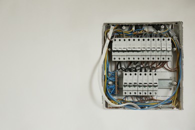 Photo of Fuse box with many electric meters and wires on light wall, space for text