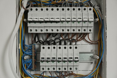 Fuse box with many electric meters and wires on light wall, closeup