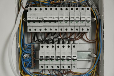 Photo of Fuse box with many electric meters and wires on light wall, closeup