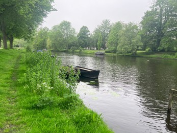 Canal with moored boats near green shore