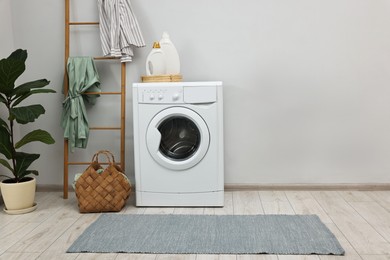 Washing machine, detergents, houseplant and ladder in laundry room, space for text