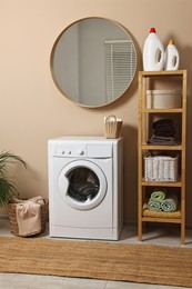 Stylish laundry room interior with washing machine, furniture and baskets