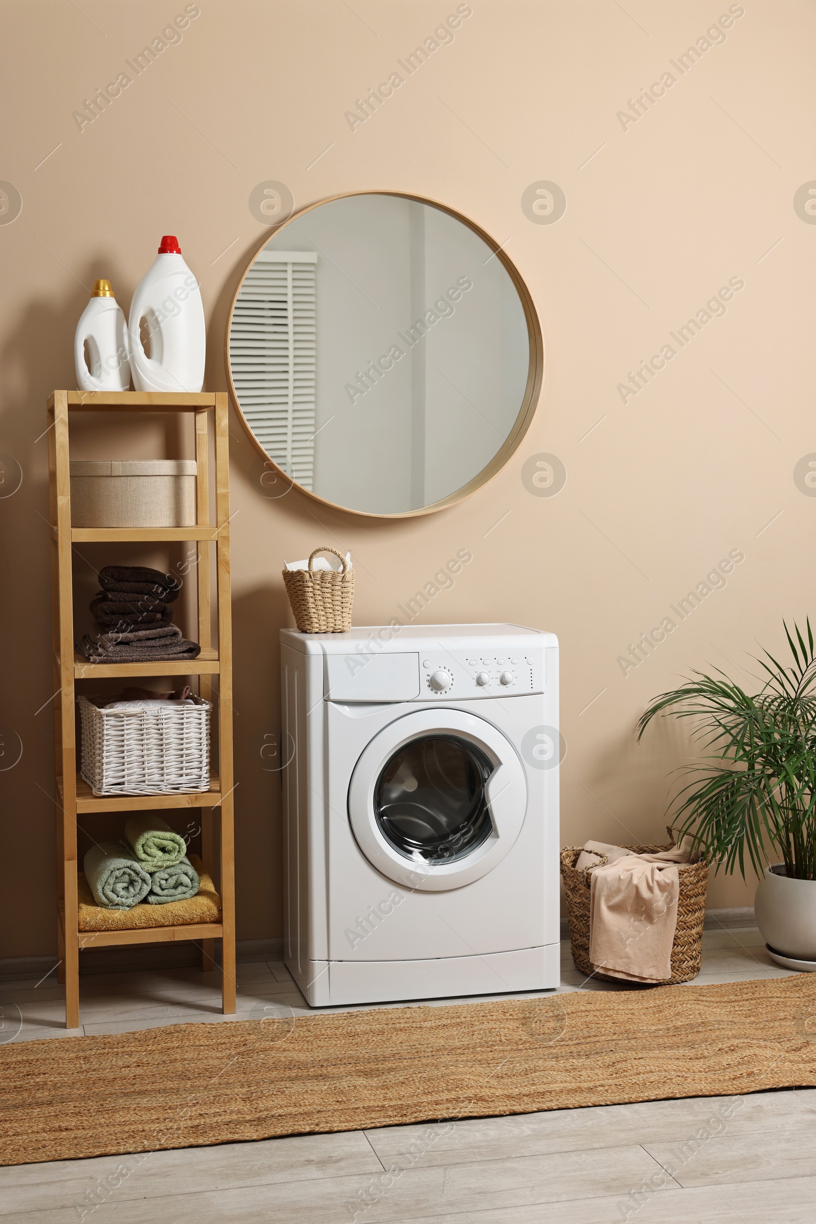 Photo of Stylish laundry room interior with washing machine, furniture and houseplant