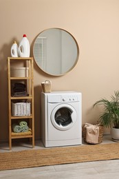 Stylish laundry room interior with washing machine, furniture and houseplant