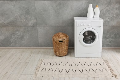 Washing machine, detergents, basket and rug in laundry room, space for text