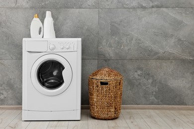 Washing machine, detergents and basket in laundry room, space for text