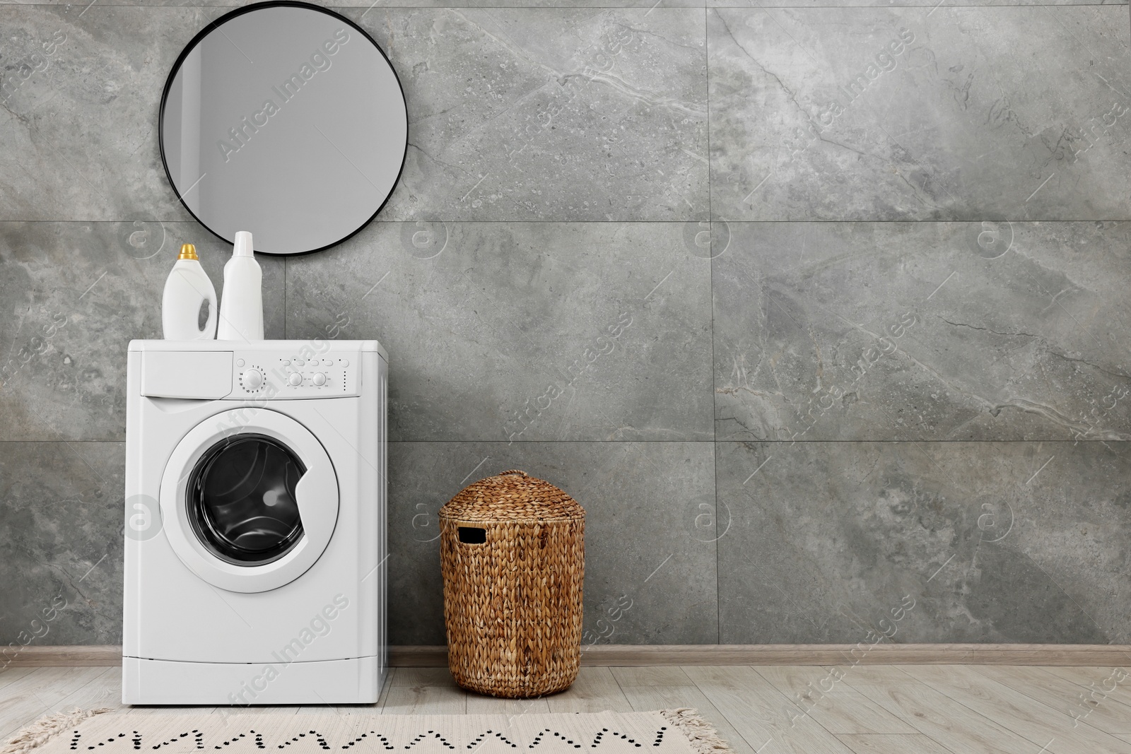 Photo of Washing machine, detergents, basket and mirror in laundry room, space for text